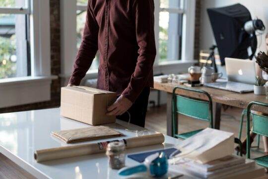 A digital nomad working on a laptop while managing an online e-commerce store, with icons representing dropshipping, Shopify, and global shipping.