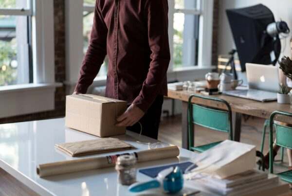 A digital nomad working on a laptop while managing an online e-commerce store, with icons representing dropshipping, Shopify, and global shipping.